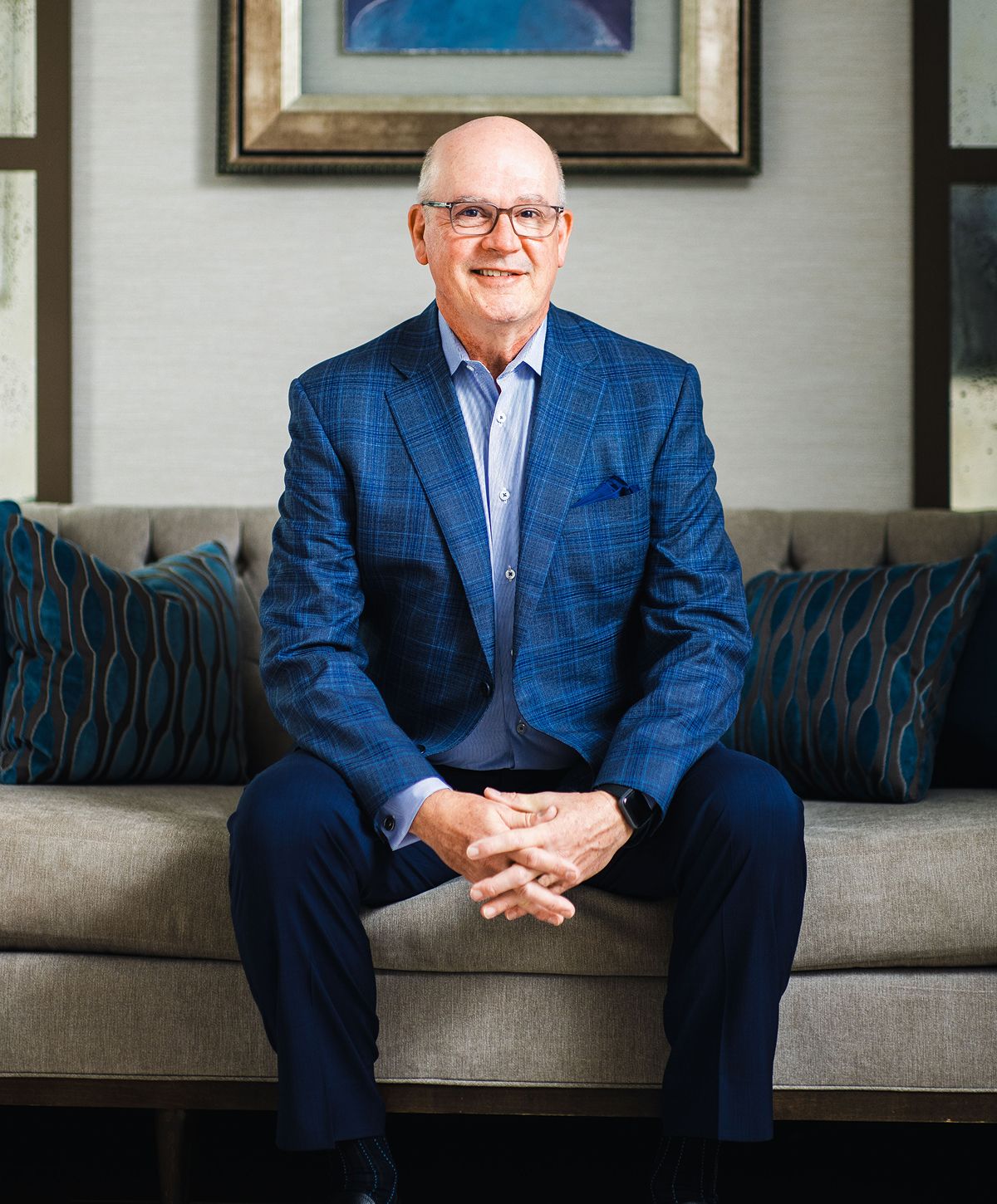 Man in blue suit sitting on couch.