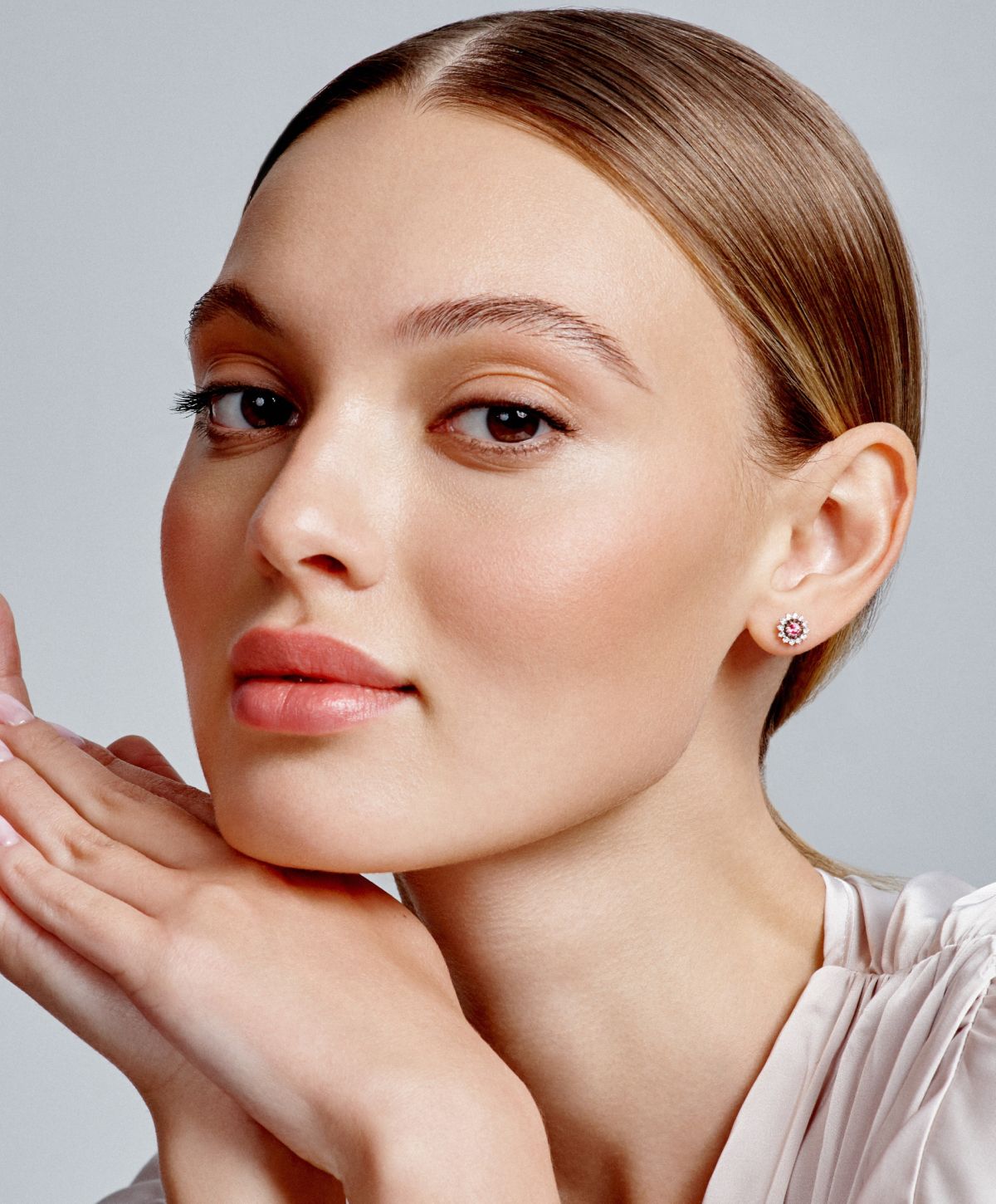 Woman modeling elegant jewelry with minimalist makeup.
