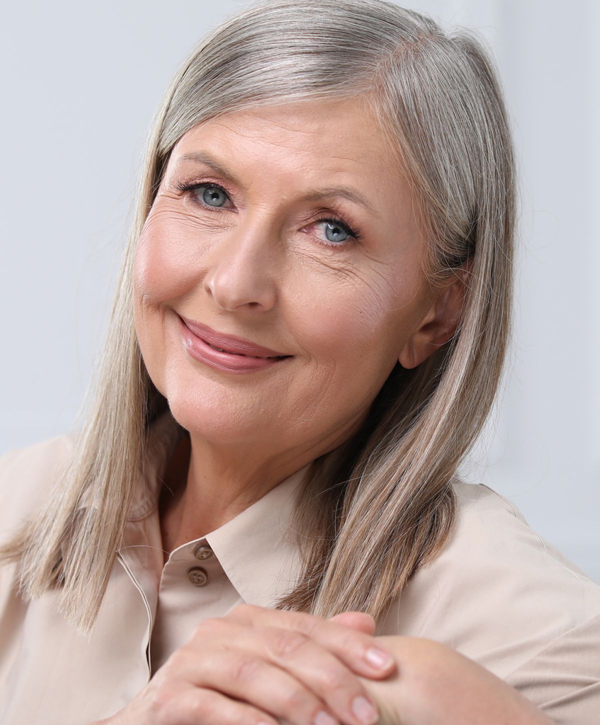 Smiling older woman with gray hair and light shirt.