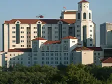 Hospital building with helicopter in the background.