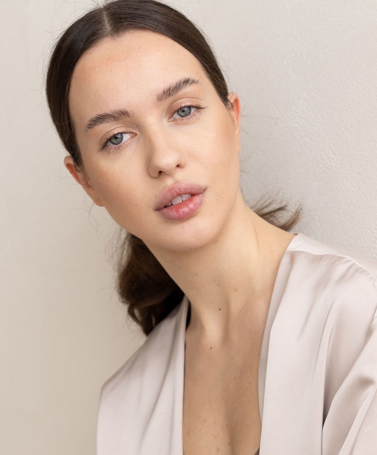 Model with light makeup against neutral background.