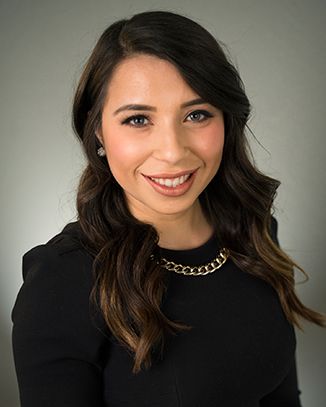 Smiling woman with long hair in black dress.