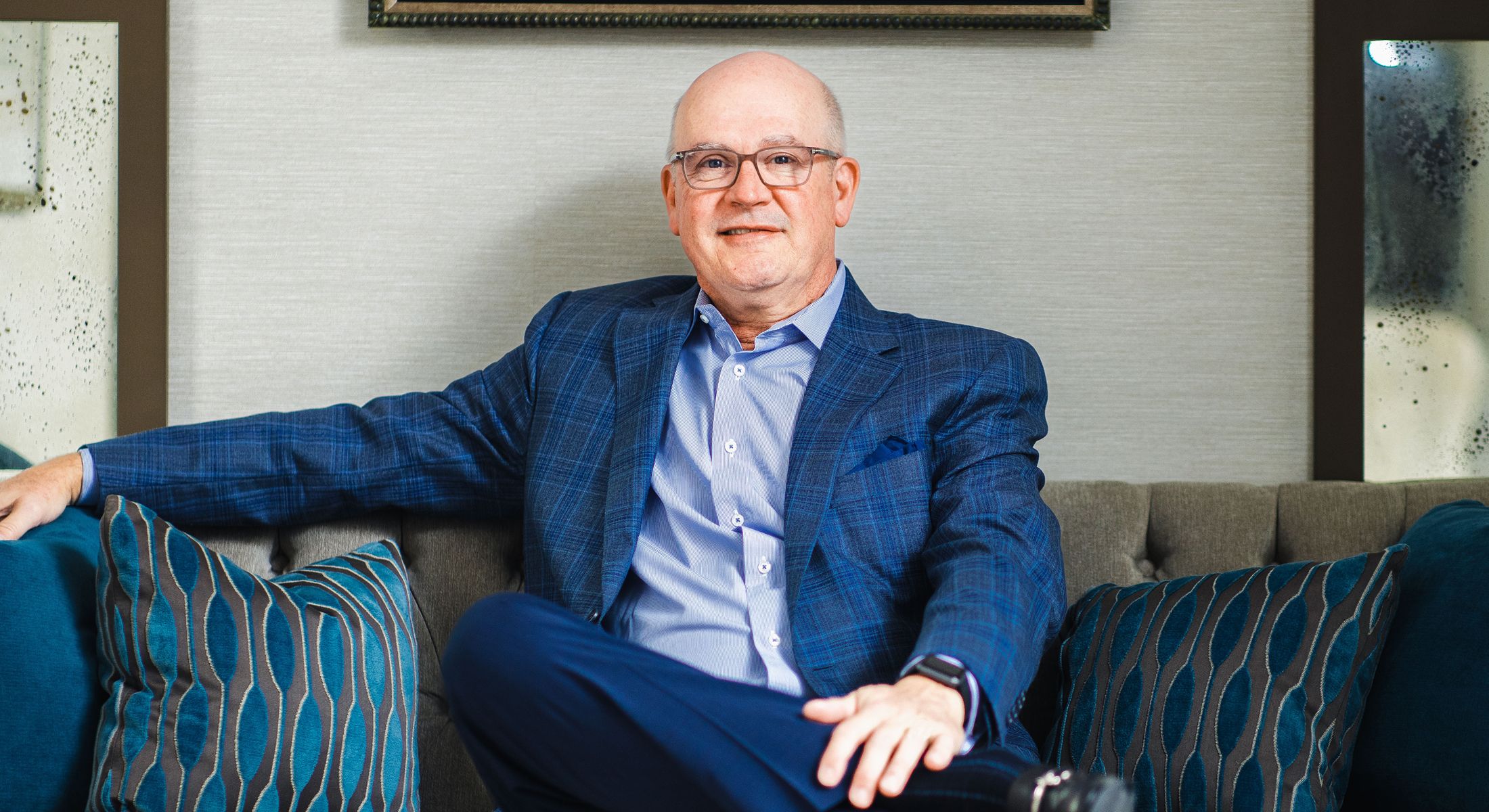Man in blue suit sitting on a couch.