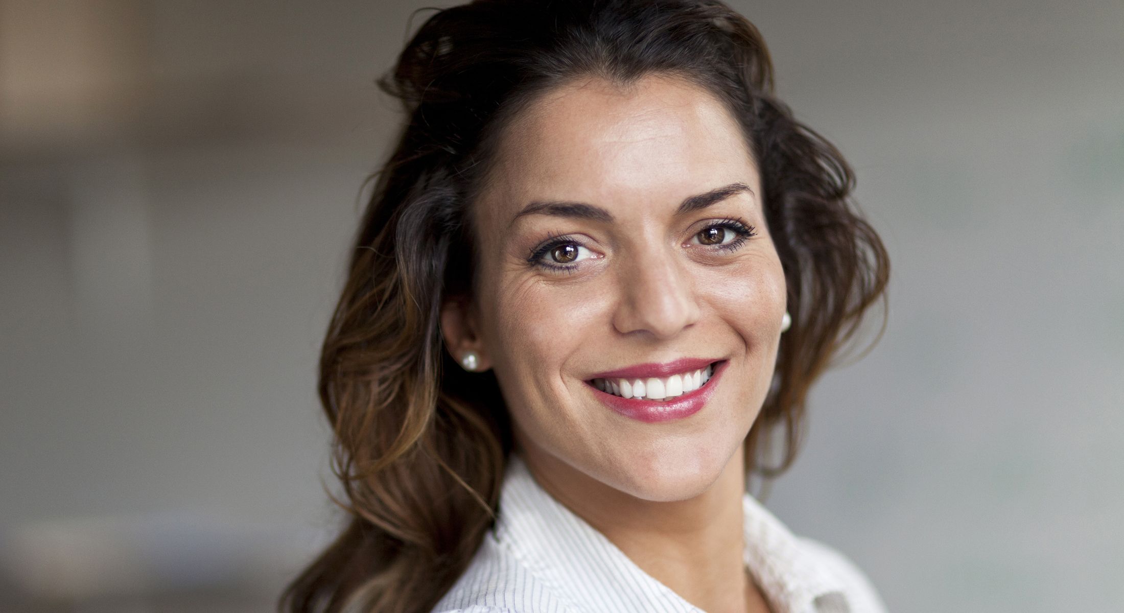 Smiling woman with wavy hair in casual setting.