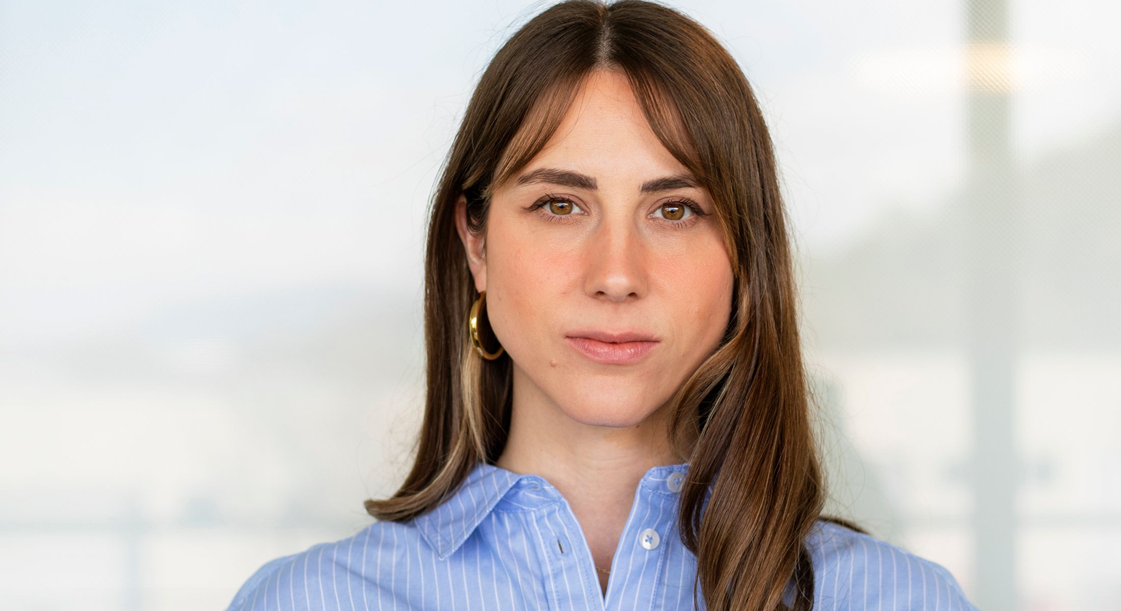 Young woman with long hair and blue shirt.