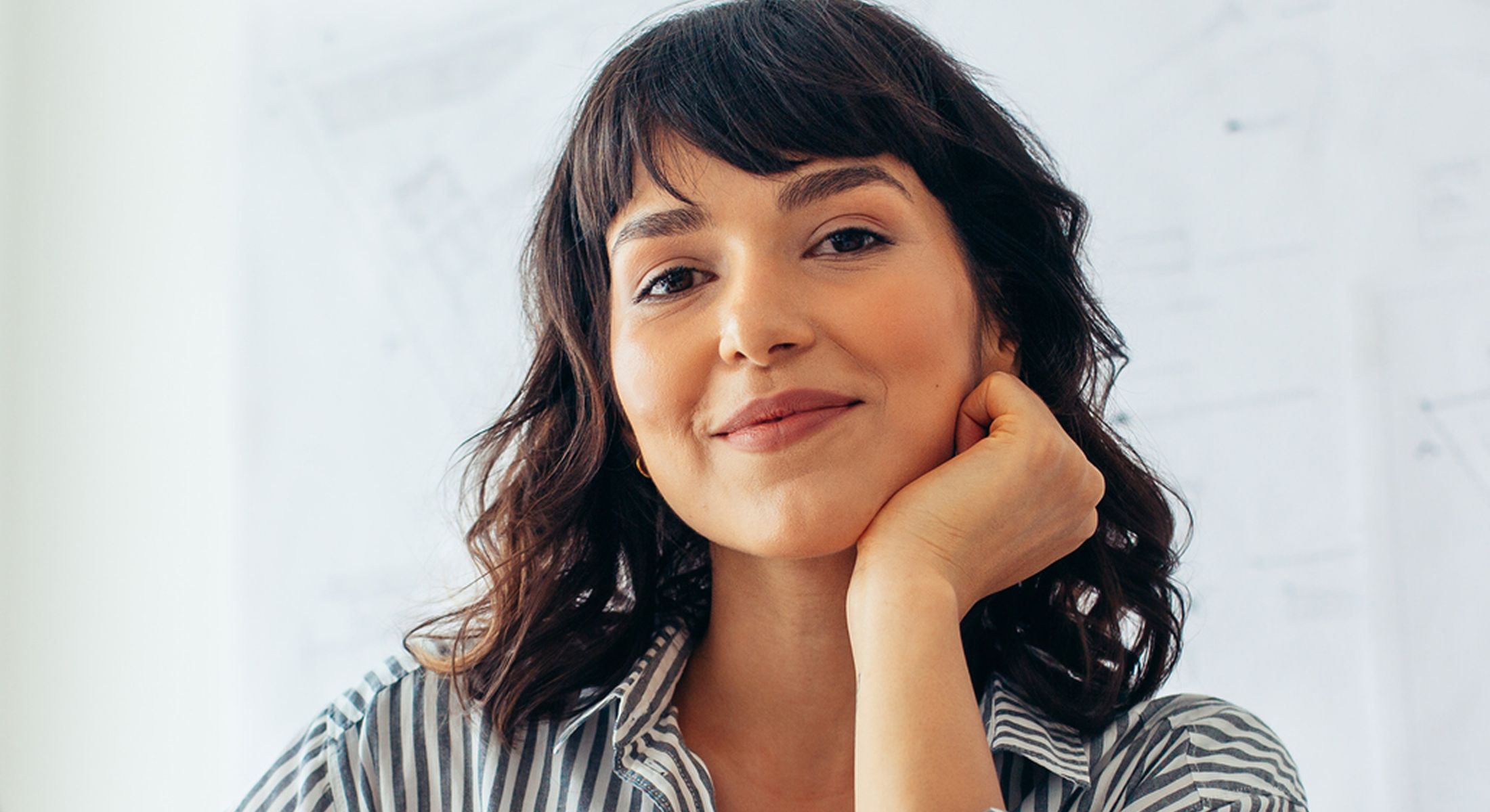 Woman smiling with hand on chin, thoughtful expression.