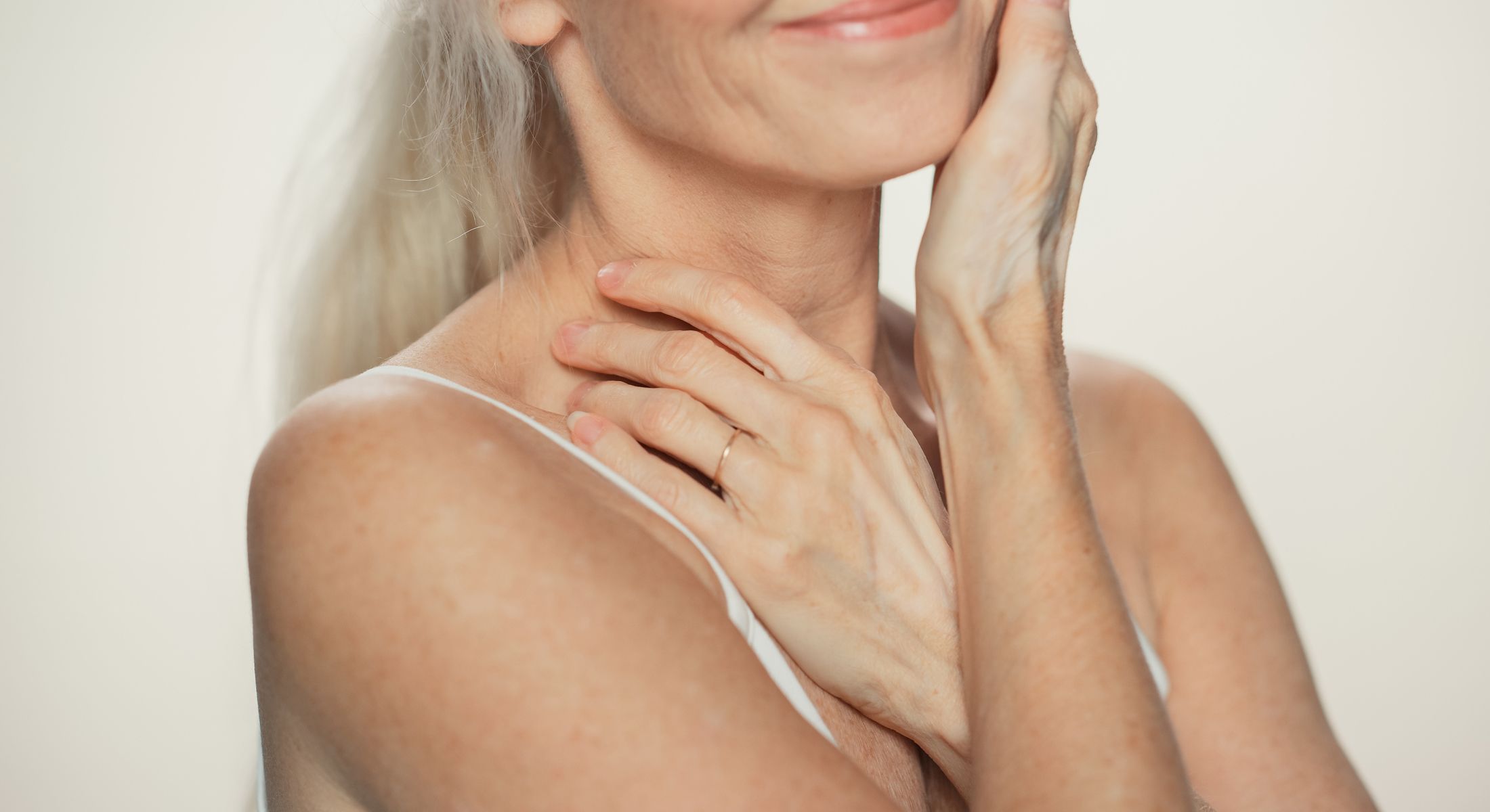 Woman gently touching her face, smiling softly.