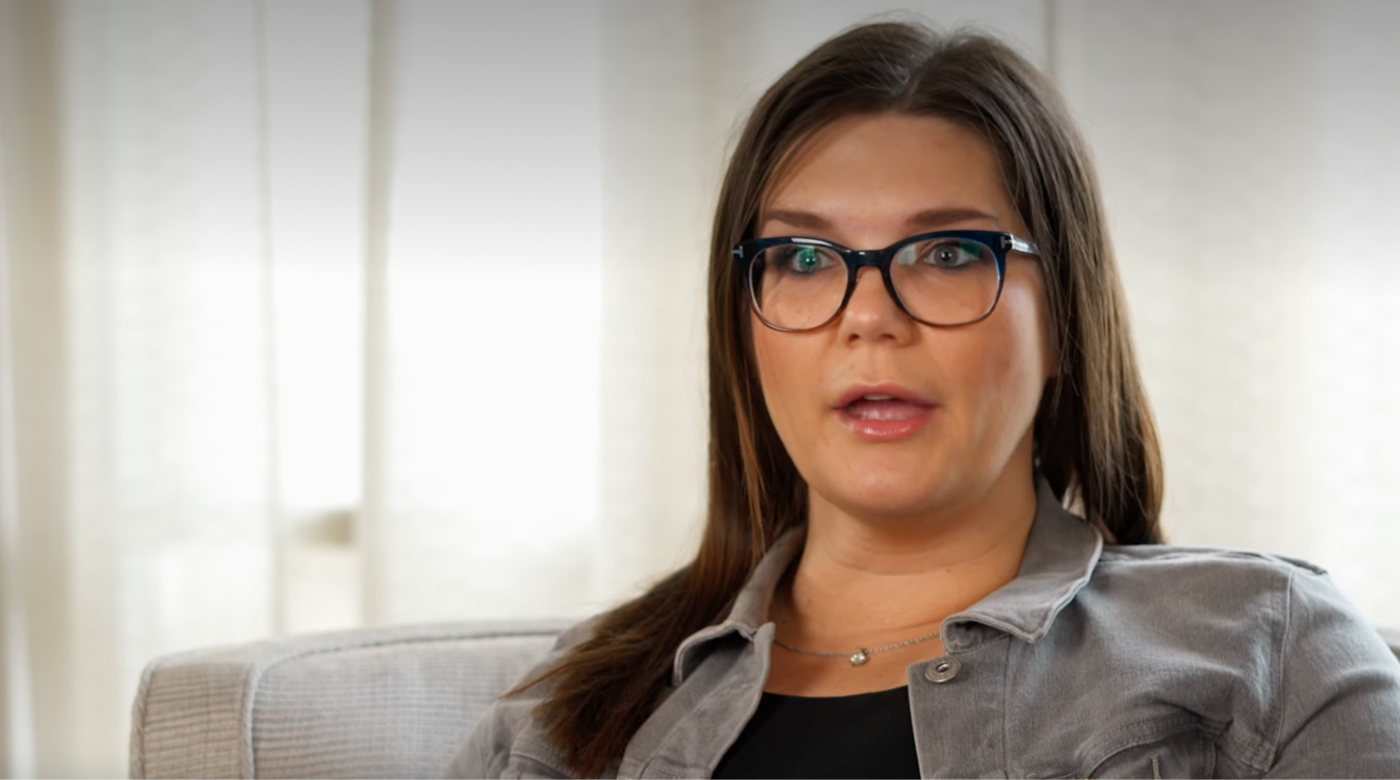 Person speaking in a casual setting with glasses.