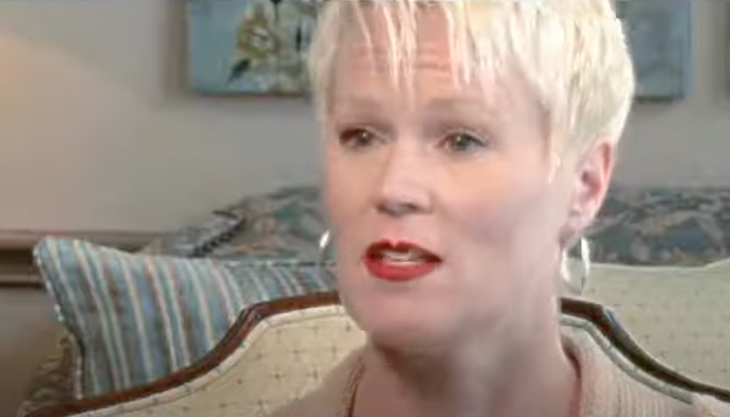 Woman with short blonde hair speaking in interview.