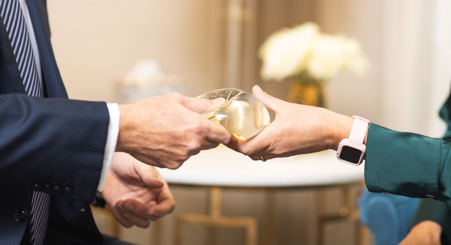 Hands exchanging a clear, rounded object.
