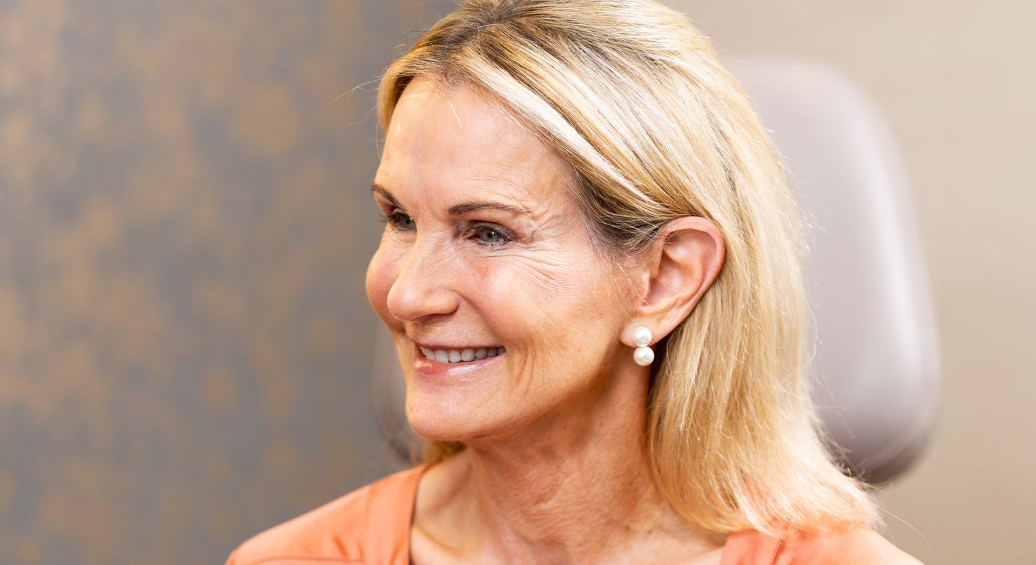 Smiling woman with blonde hair and earrings.