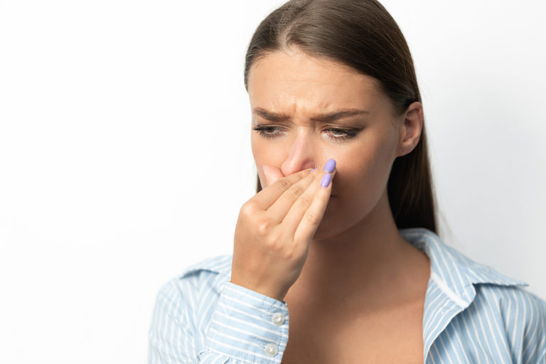 Woman touching her nose after a Rhinoplasty procedure