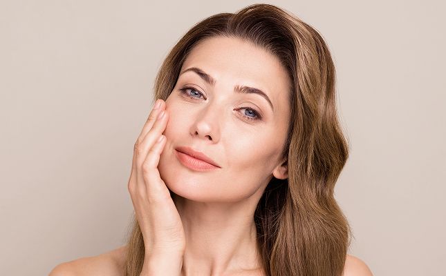 Woman touching face with natural makeup, serene expression.